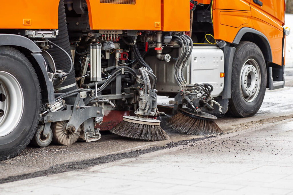 Seitliche Ansicht einer großen, orangen Straßenkehrmaschine